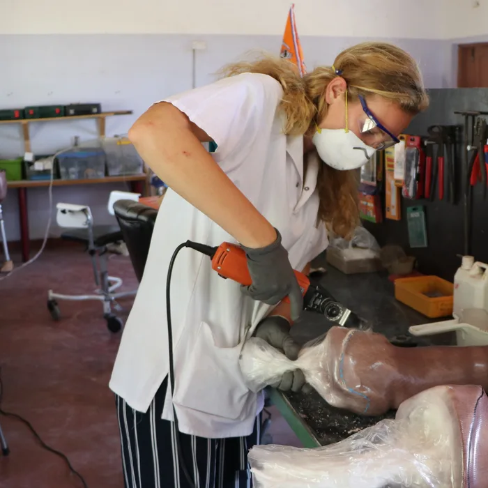 Vrijwilliger met mondkapje bewerkt een prothese in Mombasa